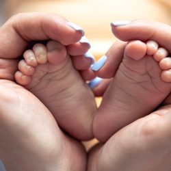 mom-holds-legs-newborn-baby-her-hands_169016-37702